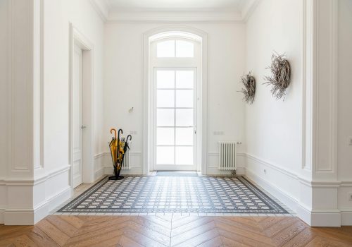 Bright foyer showcasing sophisticated interior design with parquet flooring and decor elements.